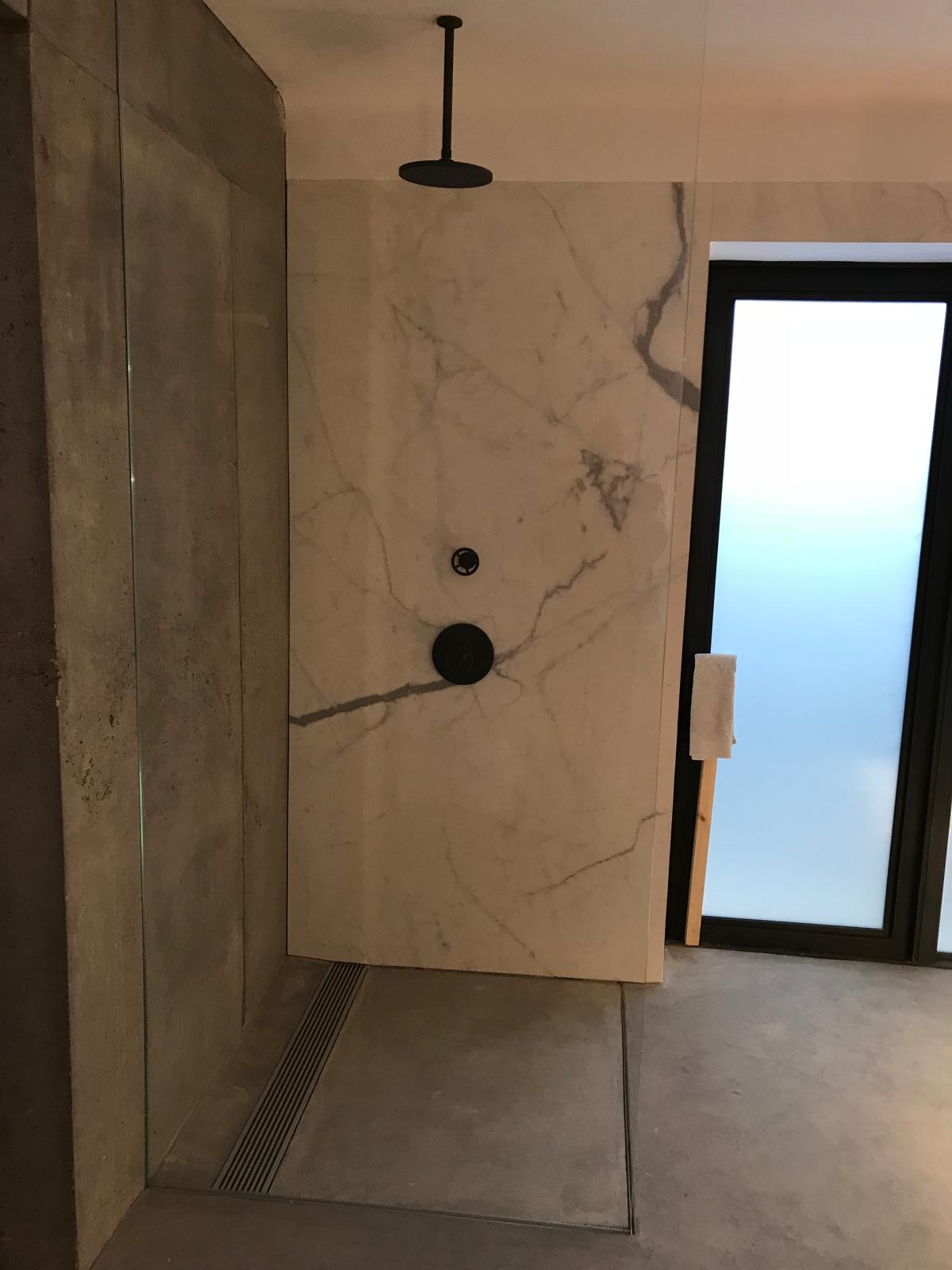 Marble effect walk-in shower with ceiling-mounted rain head and glass screen