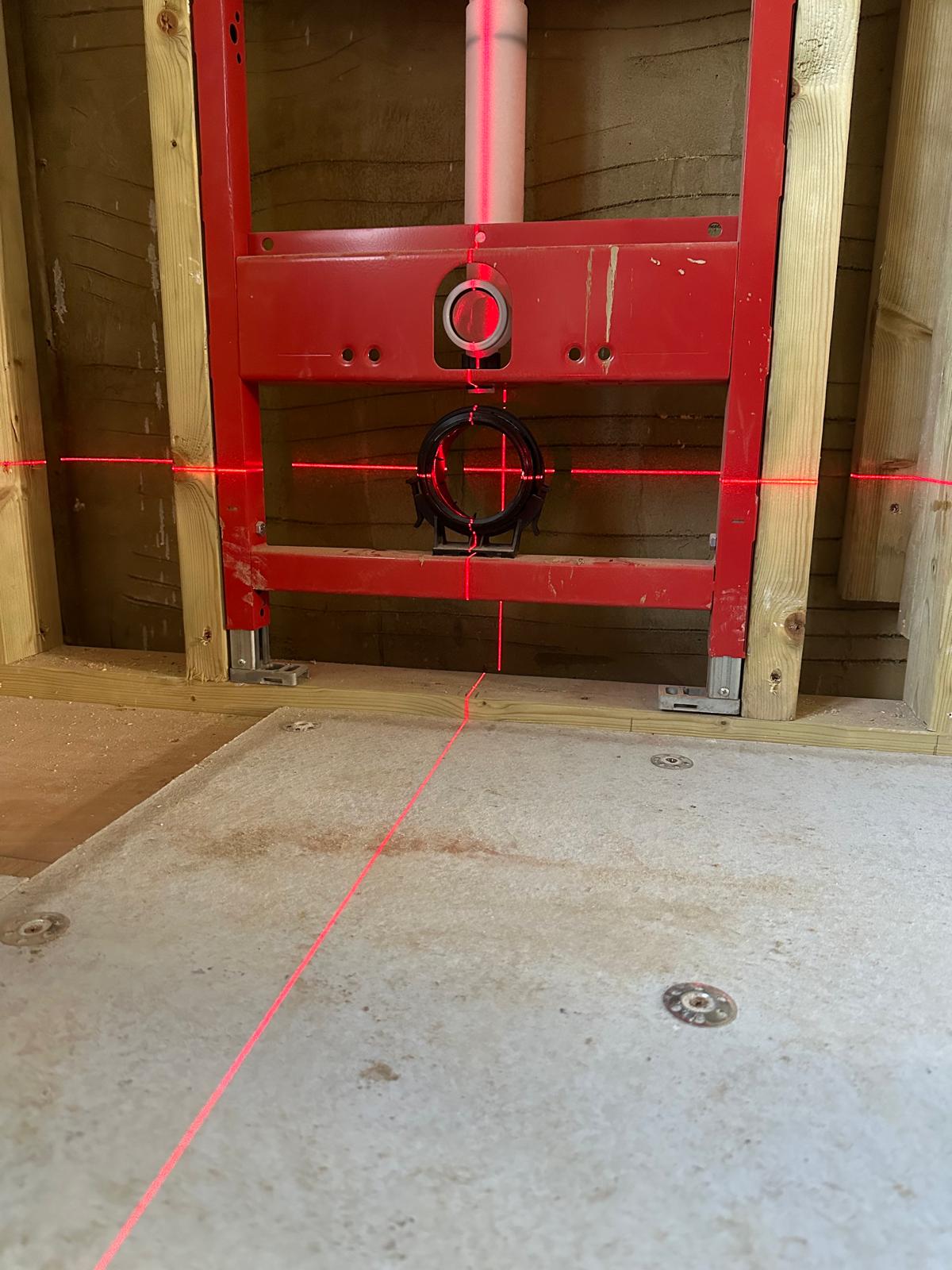 Concealed wall-hung WC frame set to laser levels during a bathroom rough-in