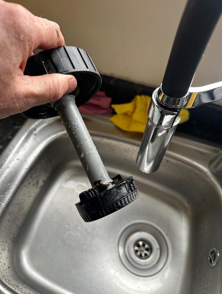 Magnetic system filter cartridge being rinsed in a sink after a powerflush