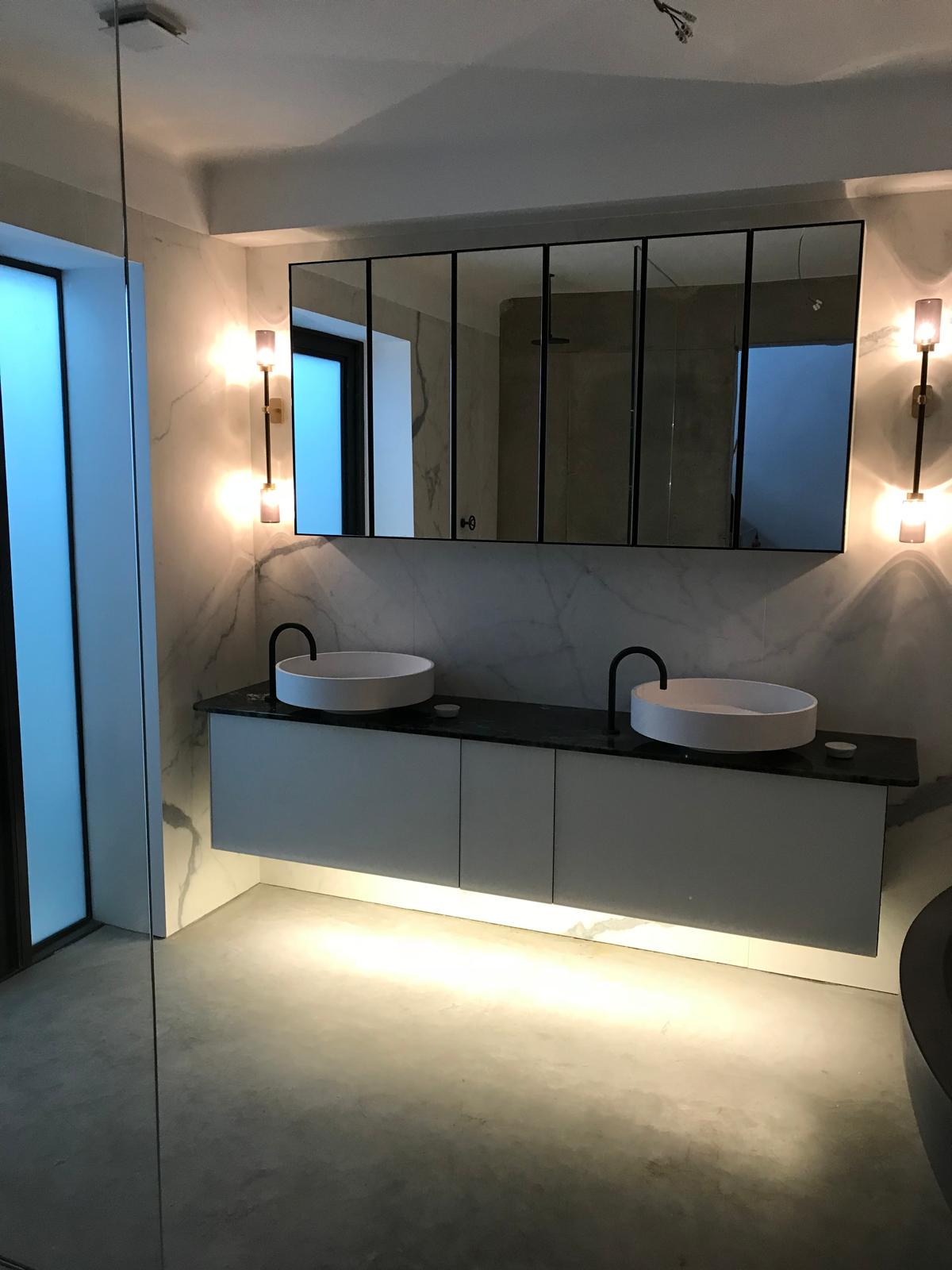 Backlit vanity unit with twin basins and mirrored cabinets in a luxury bathroom