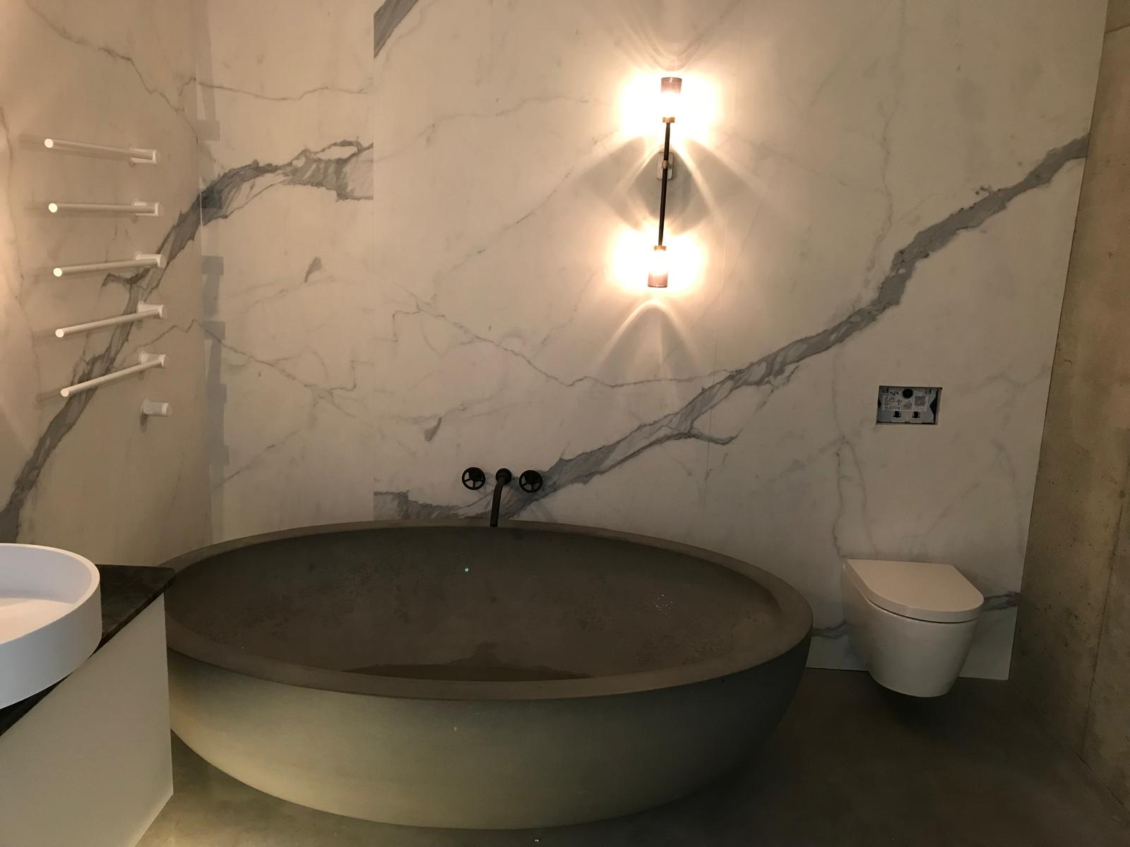 Round stone basin and back-to-wall WC in a marble effect bathroom suite