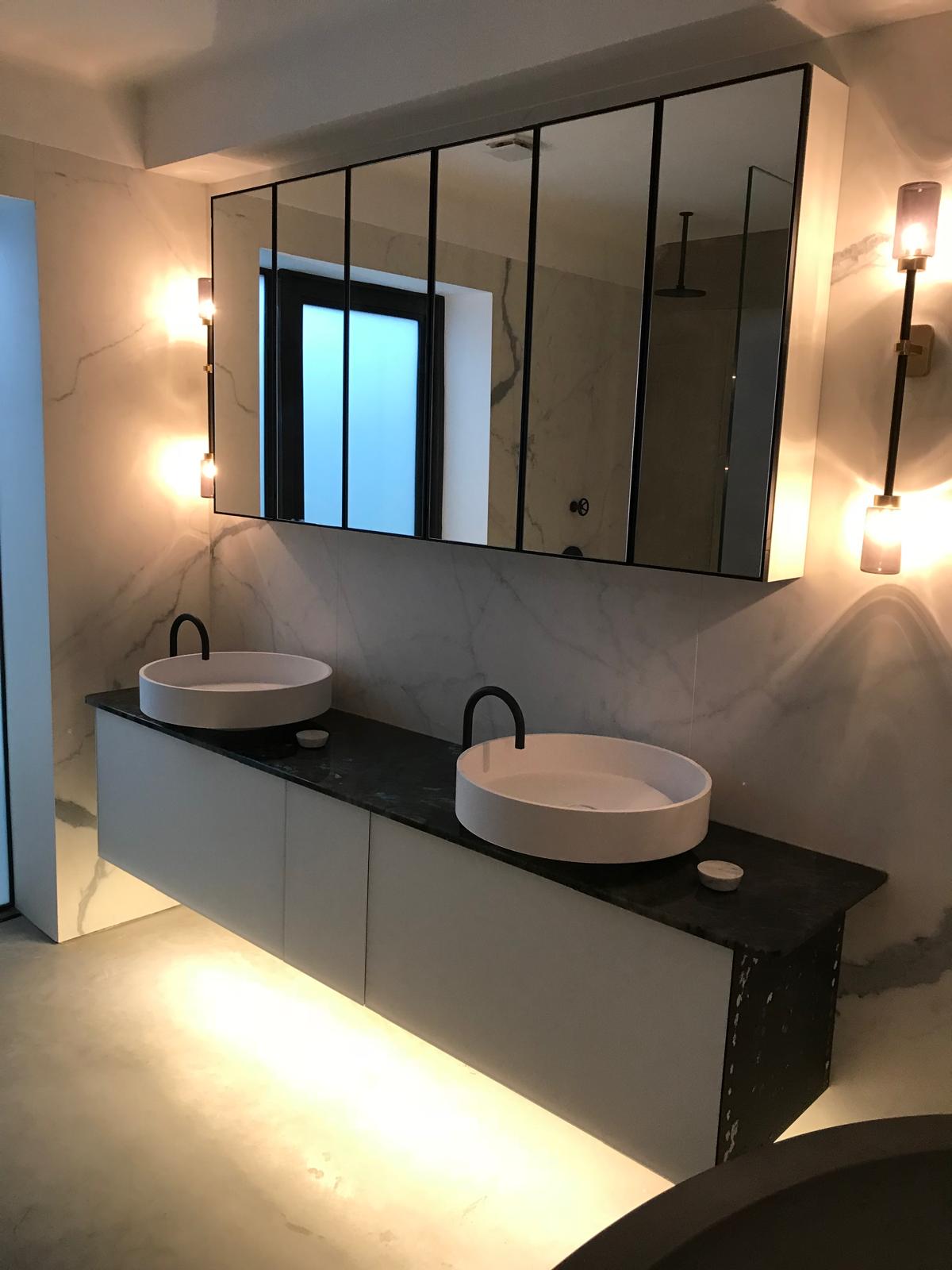 Twin basin vanity with backlit mirror in a fully tiled luxury bathroom